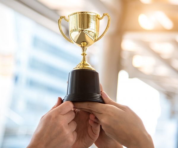Champion golden trophy for winner with sport player hands in sport stadium background. Success and achievement concept. Sport and cup award theme. American football award and match game play prize