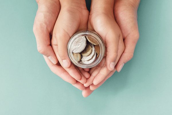 child and parent hands holding money jar, donation, saving, family finance plan concept